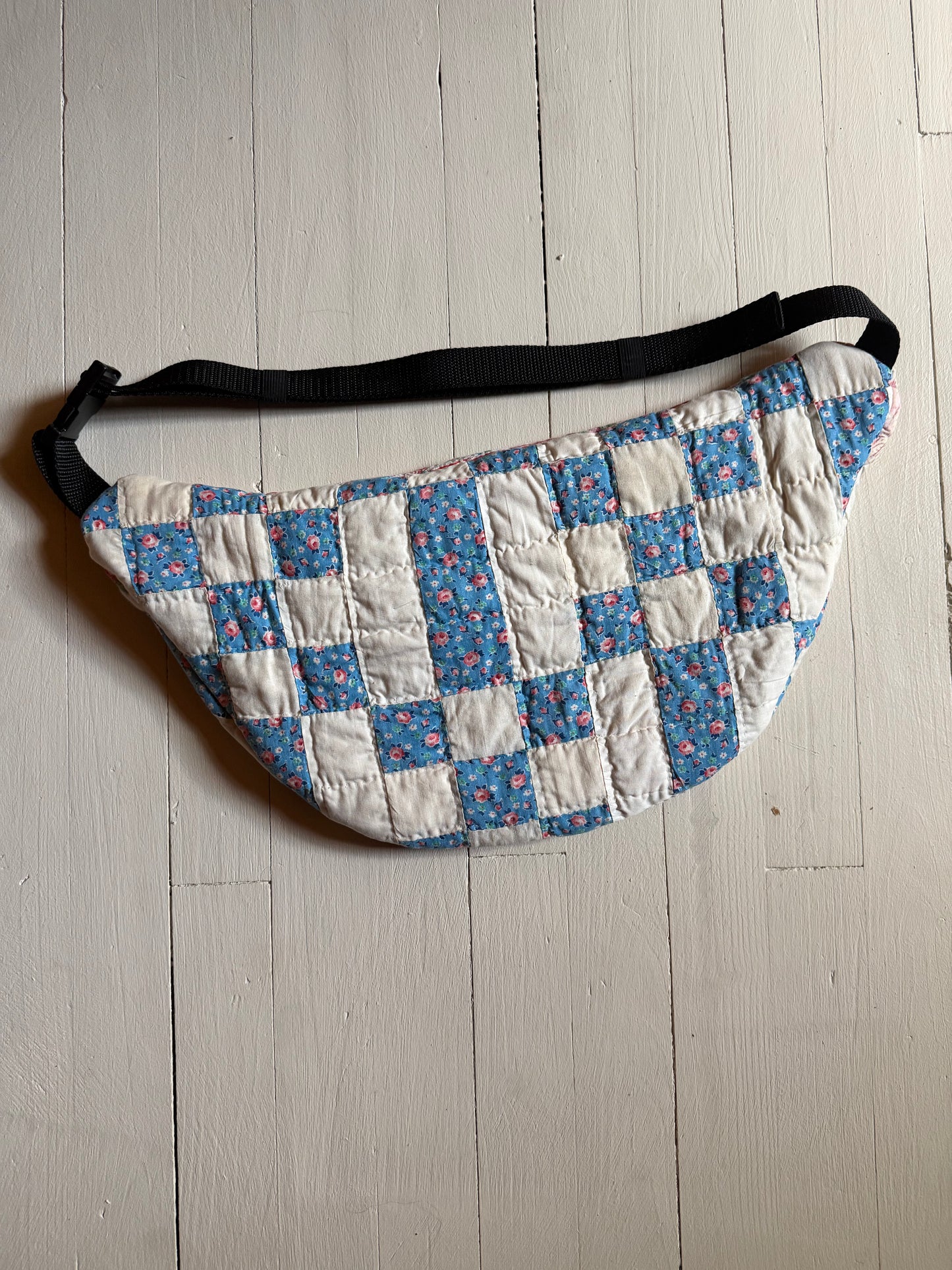 Quilted waist bag with floral pattern on a wooden floor