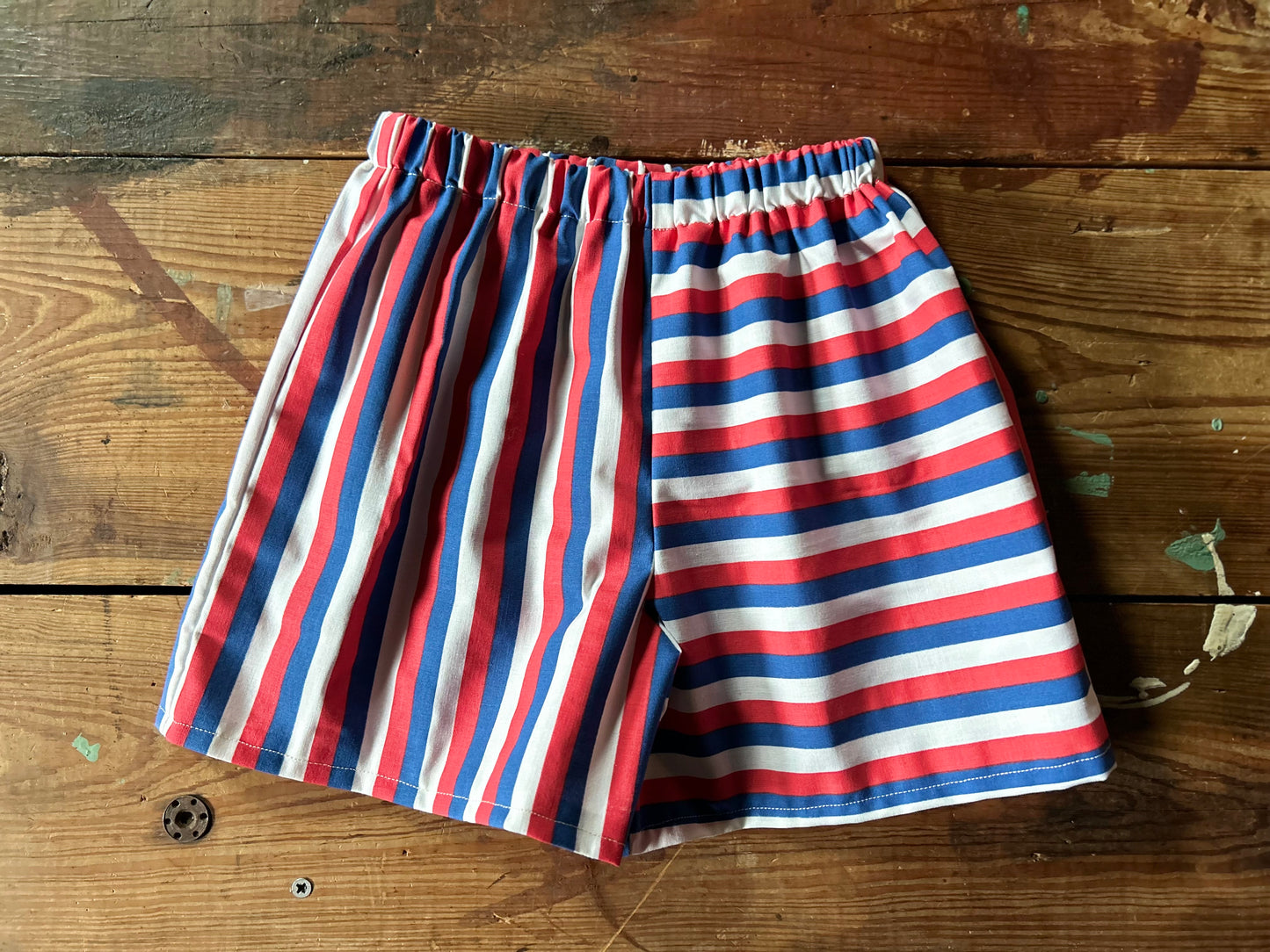 Red, white, and blue striped shorts on a wooden surface