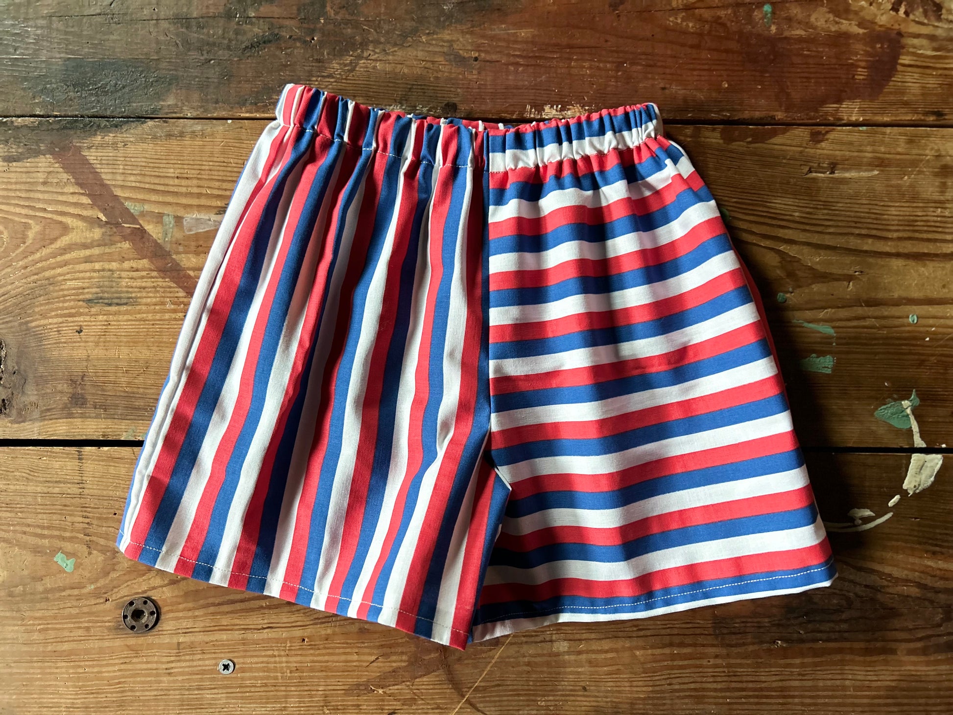 Red, white, and blue striped shorts on a wooden surface