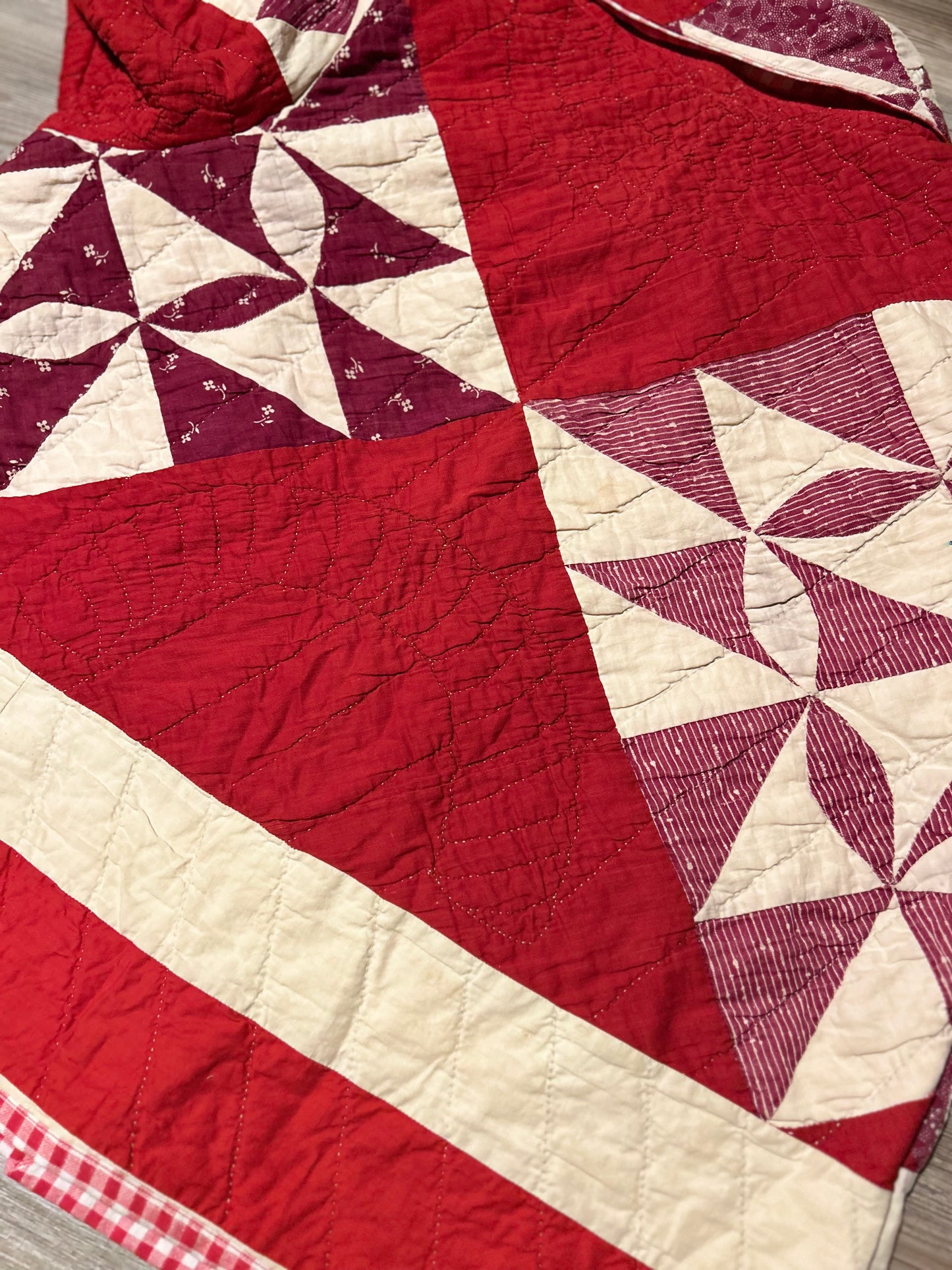 Close up of the back of a Vintage Quilted handmade jacket with red and white pattern on a light wooden floor.