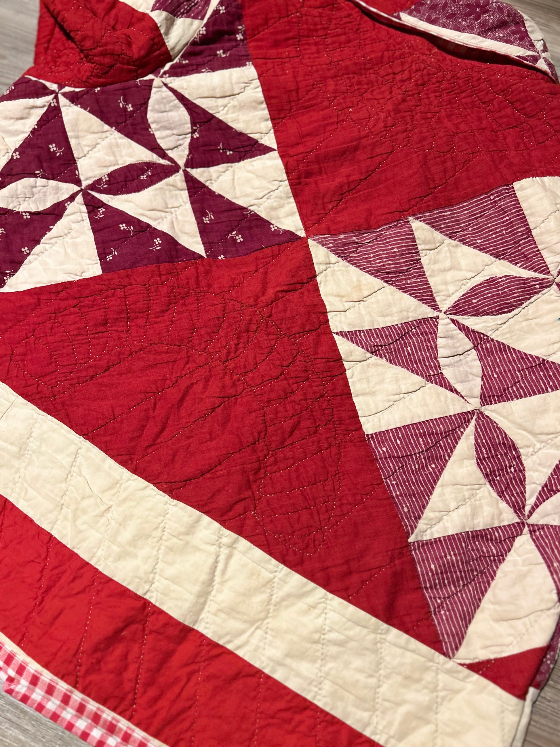 Close up of the back of a Vintage Quilted handmade jacket with red and white pattern on a light wooden floor.