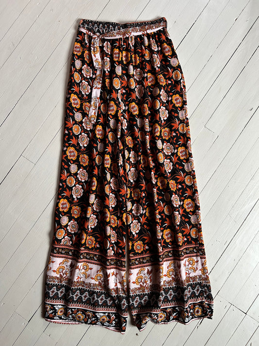 White wooded background. Black elastic pants with orange and white floral. 